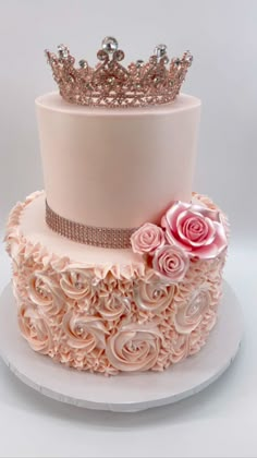 a three tiered cake decorated with pink roses and a crown on top, sitting on a white plate