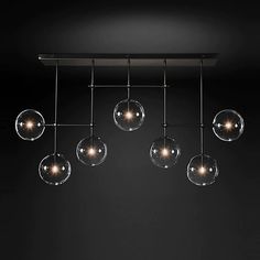 an overhead light fixture with five glass globes hanging from it's metal bar