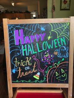 a halloween chalkboard with writing on it in front of a red chair and table