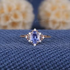 an oval cut tanzante and diamond ring on a blue blanket with fluffy balls in the background