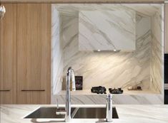 a kitchen with marble counter tops and wooden cabinets, along with stainless steel sink faucets