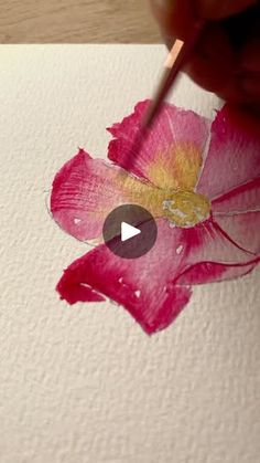 someone is painting a flower with watercolors on paper