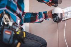 a man is holding a camera and plugging it into the wall