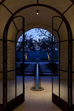 an open door leading to a large building with stairs and trees in the background at night