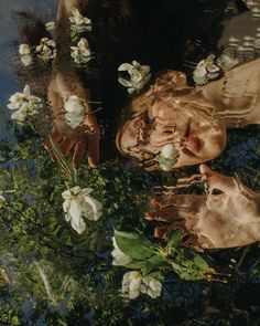 a woman is floating in the water surrounded by flowers