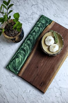 a wooden cutting board sitting on top of a table next to a potted plant