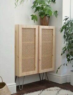 a wooden cabinet sitting next to a potted plant