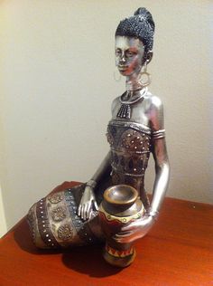 a silver statue sitting on top of a wooden table next to a vase and bowl