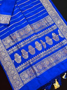 SILK MARK CERTIFIED !! Gorgeous Pure Katan Royal Blue Color with Copper and Slier Zari Work. Strips Sarees in Copper and Sliver Zari with Floral Buttas on the Pallu Soft, light weight and easy to drape Saree. The Strips are dense towards the pallu and get scattered the other end.  Item : Saree Color : Royal Blue Color Base Fabric : Pure Katan Silk  Blouse piece : Comes with Blouse piece Blouse material : Pure Katan Silk Fall & Edging (Yes/No) : Yes Comes with Silk Mark Certificate (Yes/No) : Yes Disclaimer -: - Color variation is possible due to various reasons like phone or desktop setting, resolution etc. Please don't hold us responsible. Our aim is to put the exact color of the Saree. - If the Saree is Pure Silk, we will put it very clearly in our listing that it is Pure Silk. If we do Blue Zari Weaving Traditional Party Wear, Blue Traditional Wear With Zari Weaving For Party, Blue Motif Dupatta For Celebration, Blue Dupatta With Motifs For Celebration, Blue Dupatta With Traditional Patterns For Celebration, Party Blue Banarasi Silk Saree, Blue Banarasi Silk Saree For Party, Banarasi Katan Silk Saree, Katan Silk Saree