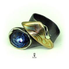 two silver rings with blue and yellow swirls in them on a white table top