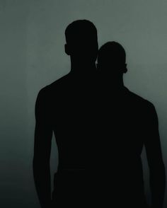 the silhouette of a man and woman in front of a white wall with a black background