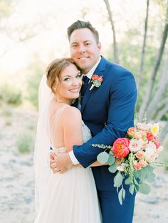 a bride and groom hugging each other in front of some trees at their outdoor wedding