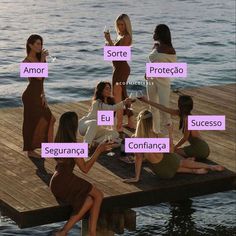 a group of women sitting on top of a wooden dock next to the ocean holding wine glasses