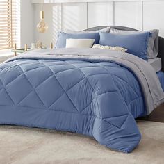 a bed with blue comforter and pillows in a bedroom setting on top of a carpeted floor