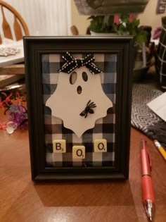 a framed photo with the word boo spelled in scrabble letters and a pen