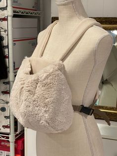 a mannequin holding a white purse in front of a mirror