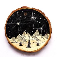 a hand painted wooden ornament with mountains and stars in the sky on it