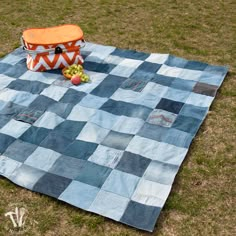 a picnic blanket on the ground with an orange basket and apples