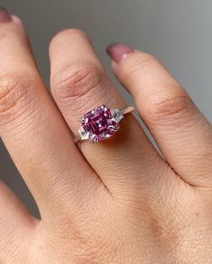 a woman's hand with a pink diamond ring on it