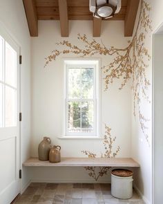 a room with a window, vases and a bench in front of the window