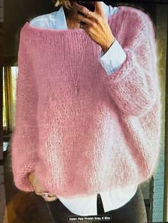 a woman taking a selfie in front of a mirror wearing a pink knitted sweater