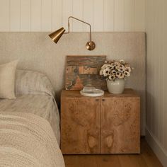 a bed room with a neatly made bed and a wooden cabinet next to it on top of a hard wood floor