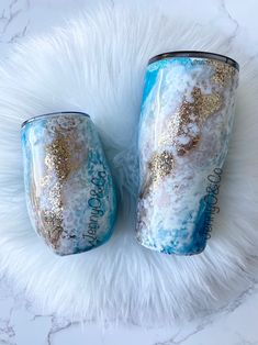 two blue and gold tumbles sitting on top of a white fur covered floor next to each other