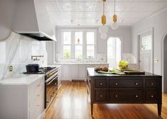 a kitchen with wooden floors and white walls, along with an island countertop that has gold pulls on it