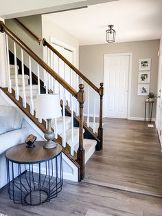 a living room with a white couch and wooden bannister next to the stairs