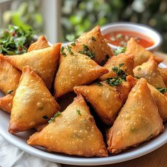 a white plate topped with fried pastries next to dipping sauce