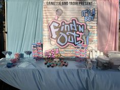 a blue table topped with lots of candy next to a wall covered in graffitti