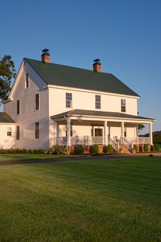 a large white house sitting on top of a lush green field