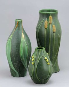 three green vases sitting next to each other on a white surface with yellow flowers