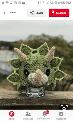 a crocheted green dragon head sitting on top of a wooden table