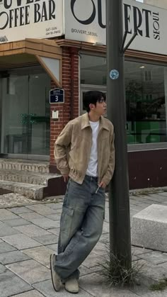 a man leaning against a pole in front of a coffee shop