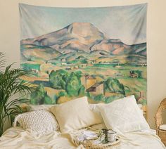 a painting on a wall above a bed with pillows and blankets in front of it