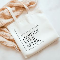 a white tote bag sitting on top of a table next to a pink scarf