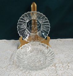 two glass dishes sitting on top of a white tablecloth covered table with doily