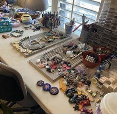 a table topped with lots of different types of buttons and bracelets next to a window