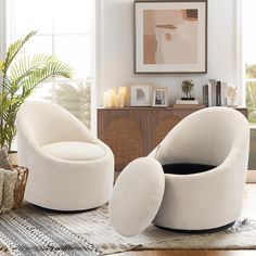 two white chairs sitting on top of a rug in a living room next to a potted plant