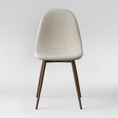 an upholstered chair with wooden legs and a seat cushion on the back, in front of a white background