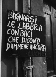 a black and white photo of a sign on a pole that says banansi le labbra con baci che diono d'ommene ancor