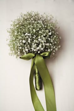 a bouquet of baby's breath tied with a green ribbon on a white wall