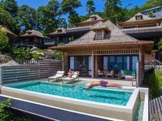 a woman swimming in a pool next to a house with an open air hot tub