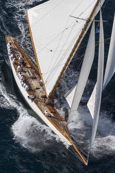 an aerial view of a sailboat sailing in the open ocean, with white sails