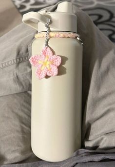 a white water bottle with a pink and yellow flower charm on it's side