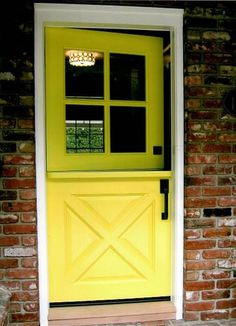 a yellow front door with two windows and a brick wall behind it is an entry way to the house