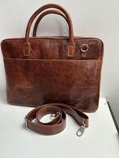 The 16 inch genuine leather laptop bag for men could have a stylish and sturdy design with durable stitching and quality metal accessories. It can have multiple compartments and pockets for organization, including a dedicated laptop compartment with a soft lining for protection. The straps could be adjustable for wearing comfort, and the genuine leather material would give it a refined look and durability. The design of the bag could be minimalist, with clean lines and subtle details, fitting an Classic Leather Laptop Bag With Sleeve, Leather-backed Laptop Bag For Office, Rectangular Leather Laptop Bag For Office, Leather-backed Rectangular Laptop Bag For Office, Rectangular Leather Laptop Bag With Leather Backing, Rectangular Laptop Bag With Leather Backing For Office, Leather Laptop Bag With Sleeve In Satchel Shape, Leather Briefcase With Laptop Sleeve For Office, Formal Leather Laptop Bag With Sleeve