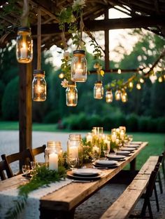 an outdoor dining table with candles and greenery hanging from the ceiling, surrounded by wooden benches