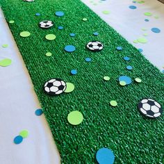 a table topped with green grass covered in soccer balls